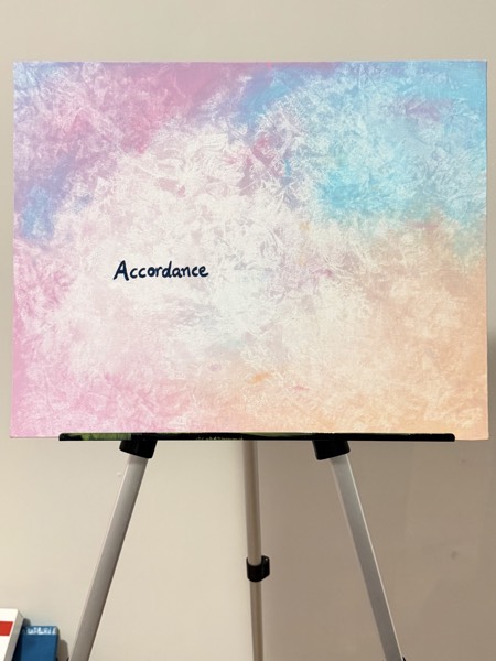 Soft abstract painting in pastel pink, peach and blue with the hand-lettered word Accordance