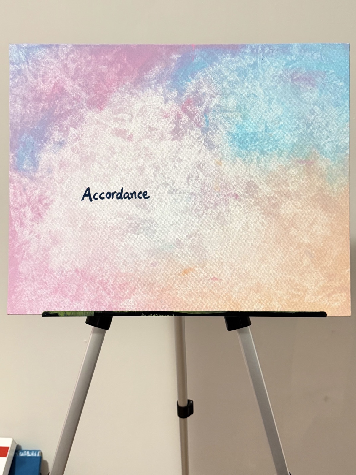 Soft abstract painting in pastel pink, peach and blue with the hand-lettered word Accordance